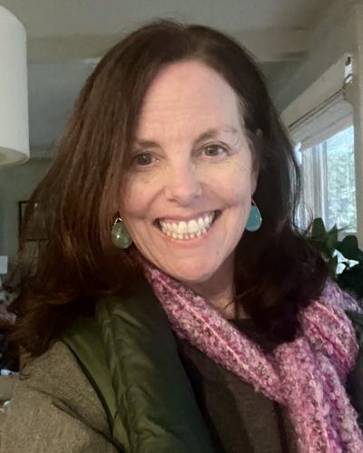 Kelly Mulligan, smiling, wearing a pink knit scarf and a green jacket